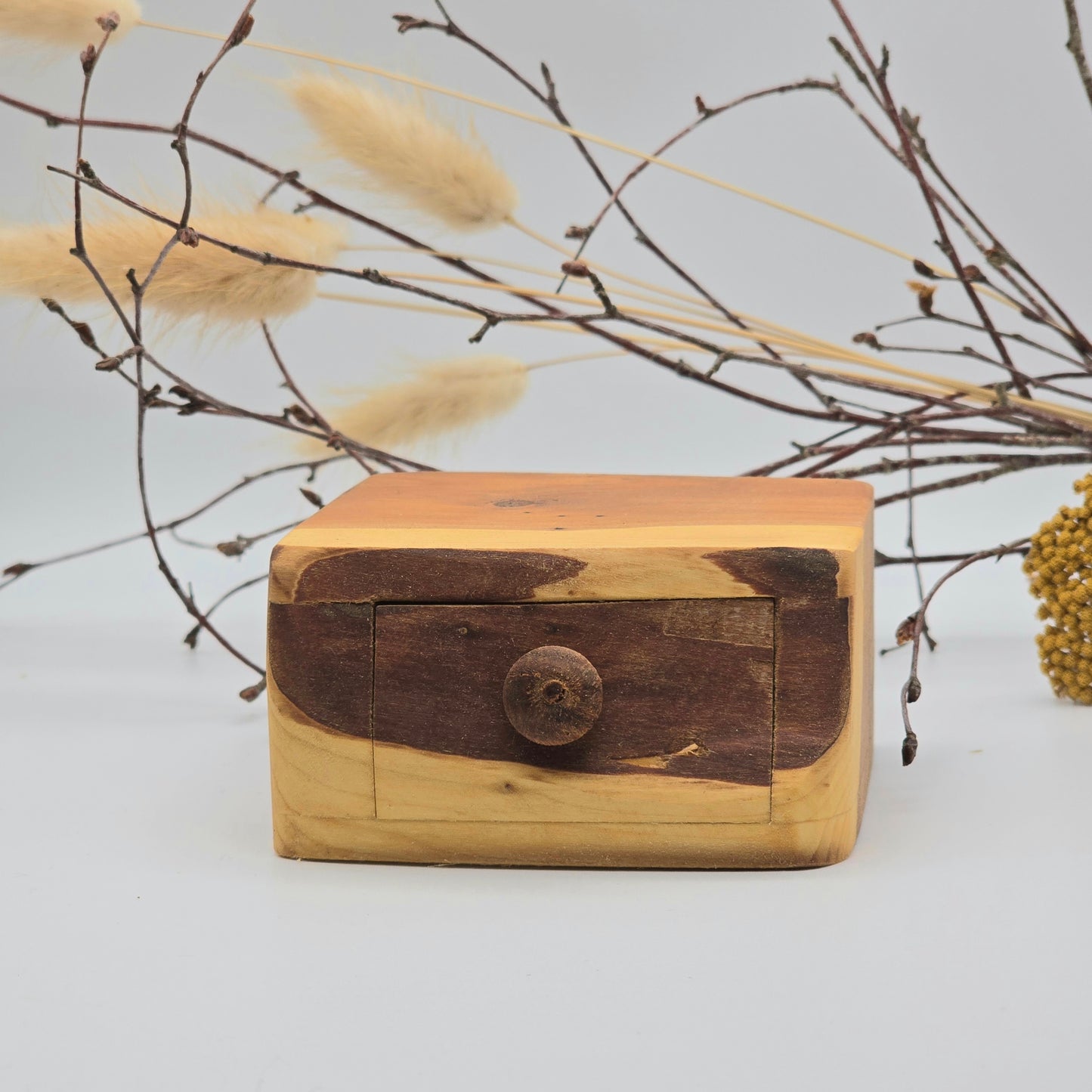 Wooden box with a rustic design on a light background with dried plants.