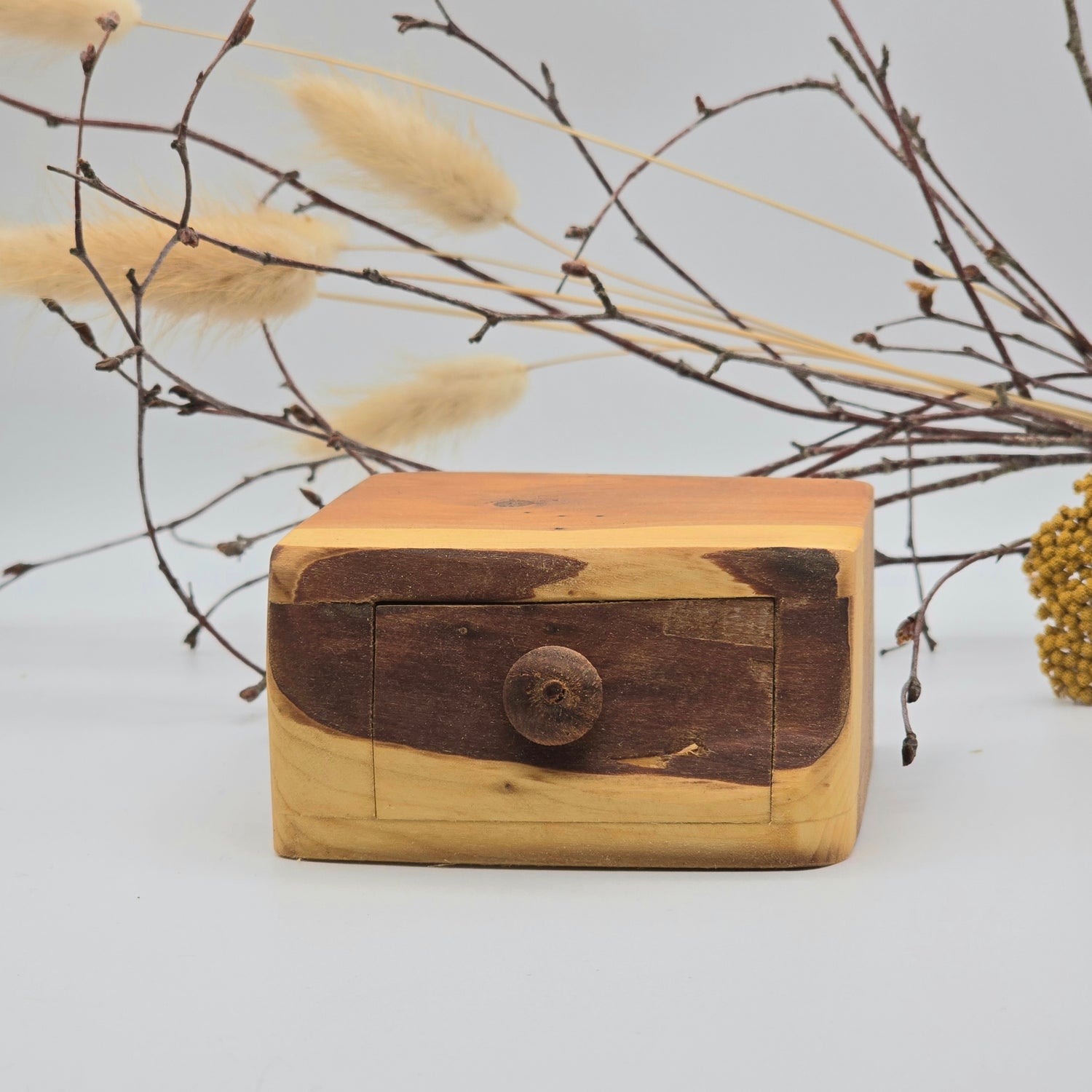 Wooden box with a rustic design on a light background with dried plants.